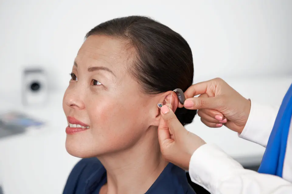 Audiologist fitting a hearing aid